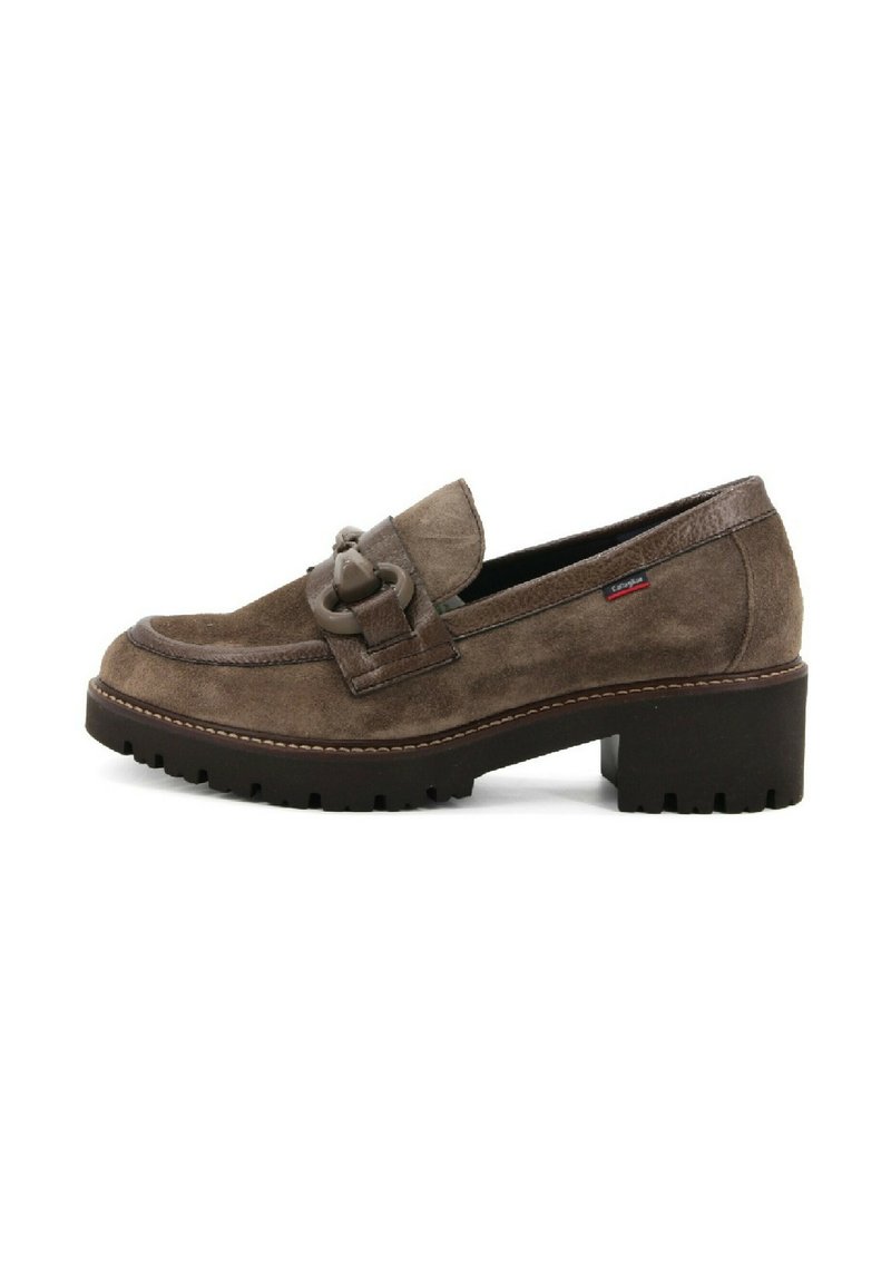 Mocasín de ante marrón con punta redondeada, detalle de hardware decorativo y suela de goma negra gruesa. Presenta costuras en los bordes.