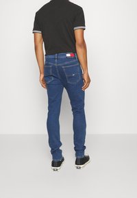 Herrskinnjeans i mörkblå denim, med en klassisk femficksdesign, stickade detaljer och en logga vid midjebandet.