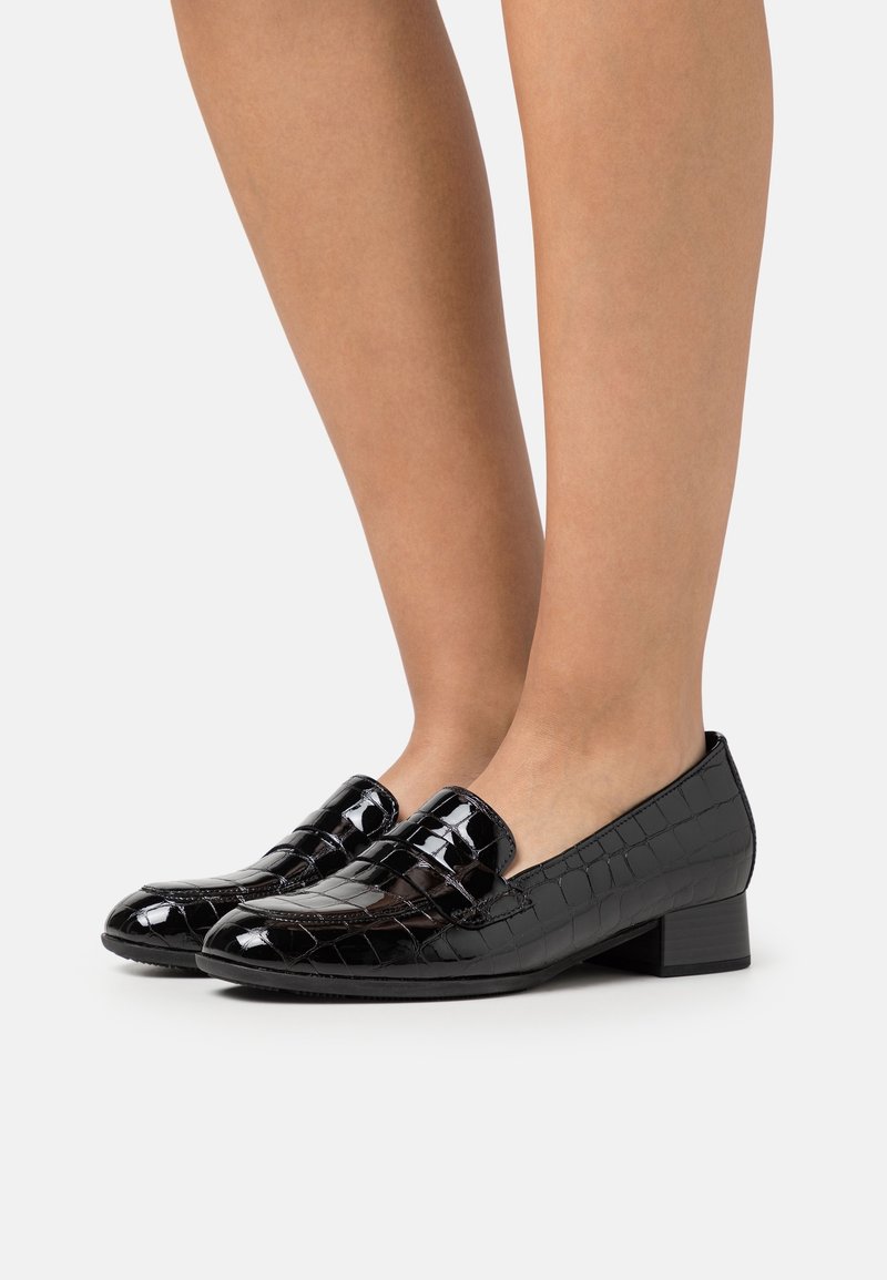 Mocassins en cuir verni noir avec une texture crocodile, talon plat et design classique, dotés d'une sangle décorative sur le dessus.