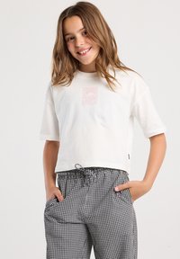 White cropped T-shirt featuring a pastel graphic print, paired with black and white checkered pants with an elastic waistband and pockets.