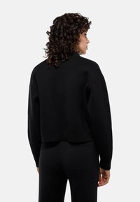 Sweatshirt noir court en maille texturée, épaules tombantes et manches larges. Sans marque visible ni motifs.