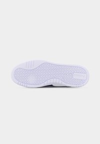 Λευκή σόλα παπουτσιού με σχέδια πέλματος σε ζιγκ-ζαγκ και ευθεία γραμμή, με λογότυπο Puma κοντά στη φτέρνα, σε μονόχρωμο λευκό φόντο.