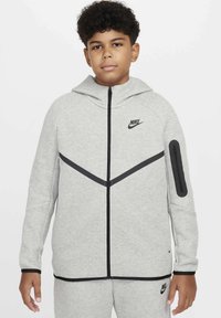 Felpa grigia Nike con zip frontale, accenti neri e tasca laterale. Presenta un cappuccio aderente, maniche lunghe e un design geometrico.