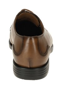 Chaussure en cuir marron avec un talon arrondi, texture lisse et coutures décoratives. Dotée d'une languette à l'arrière pour un enfilage facile.