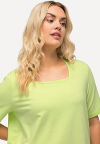Top corto a maniche corte verde lime con scollatura quadrata. Realizzato in un tessuto morbido con una texture liscia, presenta una vestibilità comoda e senza motivi.