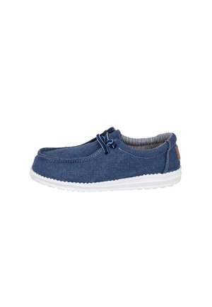 Zapato casual azul marino tipo slip-on con suela blanca, forro interior a rayas y cordones elásticos en el lateral.