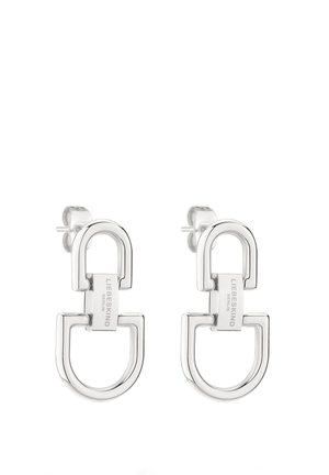 Boucles d'oreilles en métal argenté avec un design géométrique à boucles interconnectées, finition lisse et accent de marque.