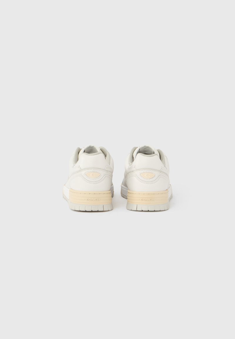 White sneakers with a smooth leather upper, cream-colored midsole, and textured rubber outsole. Features padded collars and minimal branding.