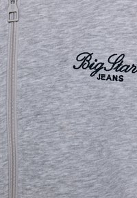 Siva zip-up sweatshirt narejen iz mehkega, teksturiranega blaga. Ima izvezen logotip "Big Star" in "JEANS" v kontrastni črni nitki.