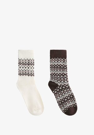 Een paar sokken: de ene crème met een geometrisch bruin patroon, de andere donkerbruin met een gestructureerd wit ontwerp, die contrasterende patronen tonen.