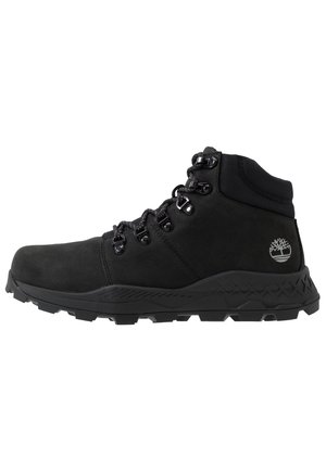 Botte de randonnée noire à tige haute avec semelle robuste, œillets métalliques pour lacets, col rembourré à la cheville et logo Timberland sur le côté du talon.