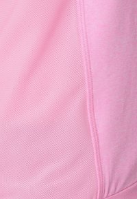 Jasnoróżowa tkanina sportowa o fakturze siateczki. Zawiera przeszywane szwy, podkreślające strukturę ubrania.