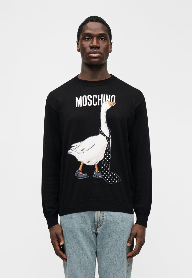 Schwarzer Pullover mit gesticktem Gänse-Motiv, das eine gepunkte Krawatte und Schuhe trägt. "MOSCHINO"-Logo über dem Design. Weiche Textur.