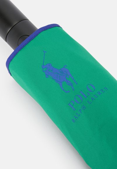 Zöld anyagú ernyőhüvely kék díszítéssel, pólójátékos grafikával és kék "POLO RALPH LAUREN" felirattal. Fekete fogantyú jól látható.
