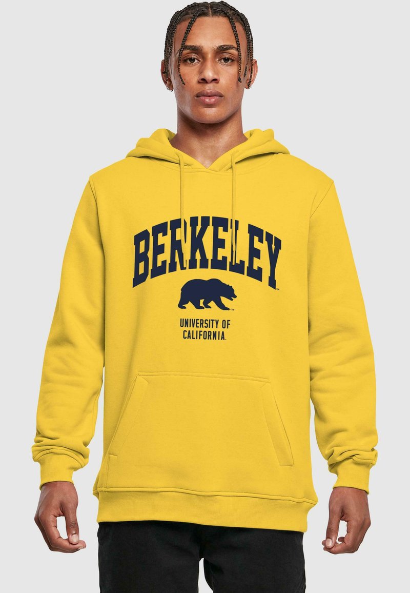 Kollane kapuutsi pusa, millel on nöörid ja esikott, ning millel on sinise kaarekirjaga tekst "BERKELEY" ja karu graafika all.