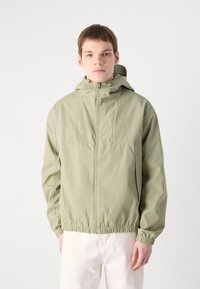 Light green, lightweight hooded jacket with front zip, elastic cuffs, and a cinched hem, designed with a minimalist aesthetic.
