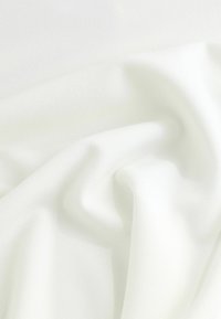 Biały materiał o miękkiej, gładkiej teksturze, z delikatnymi fałdami i zagnieceniami. Materiał wydaje się lekki i lekko przezroczysty.