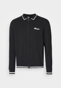 Cardigan nero con texture a coste, chiusura con zip e strisce bianche col colletto e ai polsini. Presenta il logo "Dickies" ricamato sul petto.