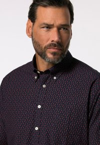 Camisa de botones azul marino con un pequeño patrón floral rojo, que presenta un cuello, un bolsillo de parche y botones blancos en el frente.
