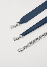 Three detachable bag straps, two blue leather with silver hardware, and one metal chain with oval links and a polished finish.