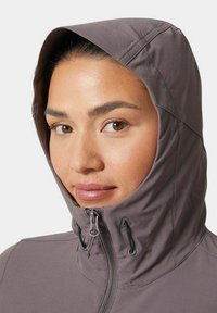 Chaqueta gris con capucha, cierre frontal y cordones ajustables. Presenta una tela suave y ligera, además de una capucha que se ajusta bien.