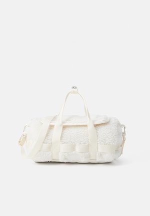 White fleece bag with a textured surface, featuring dual top handles, adjustable strap, and side clip. Seam detailing and logo on front.