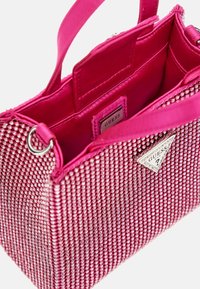 Vaaleanpunainen käsilaukku, jossa on teksturoitu pinta ja upotettuja strasseja, kaksinkertaiset kahvat sekä metallinen logo yksi puoli. Sisäpuoli on sileä.