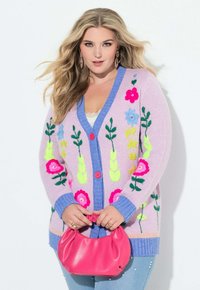 Lila gebreid vest met levendige bloemrijke borduursels in roze, blauw en groen. Heeft een diepe V-hals en roze knopen; gecombineerd met een roze handtas.