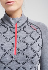 Grå quarter-zip pullover med et tekstureret mønster af "DOVRE" logoet. Har en kontrasterende pink lynlås og sort syning langs sømmene.