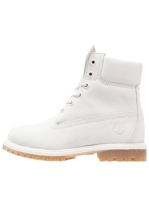 Witte leren veterschoen met padded boord en tan rubberen zool, Timberland-logo gegraveerd aan de zijkant.