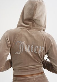 Cappuccio corto in velluto marrone con logo "Juicy" in strass sul retro, dotato di cappuccio e design aderente. Texture liscia e aspetto morbido.