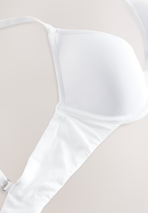 Valge rinnahoidja, millel on sile kangas, vormitud tissid, reguleeritavad rihmad ja haakeseadisega kinnis. Iseloomustab õmblusteta disain, mis tagab puhta välimuse.