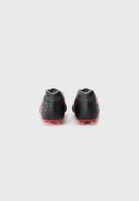 Black football boots with red accents, featuring a textured leather finish, rear heel support, and translucent outsole studs.