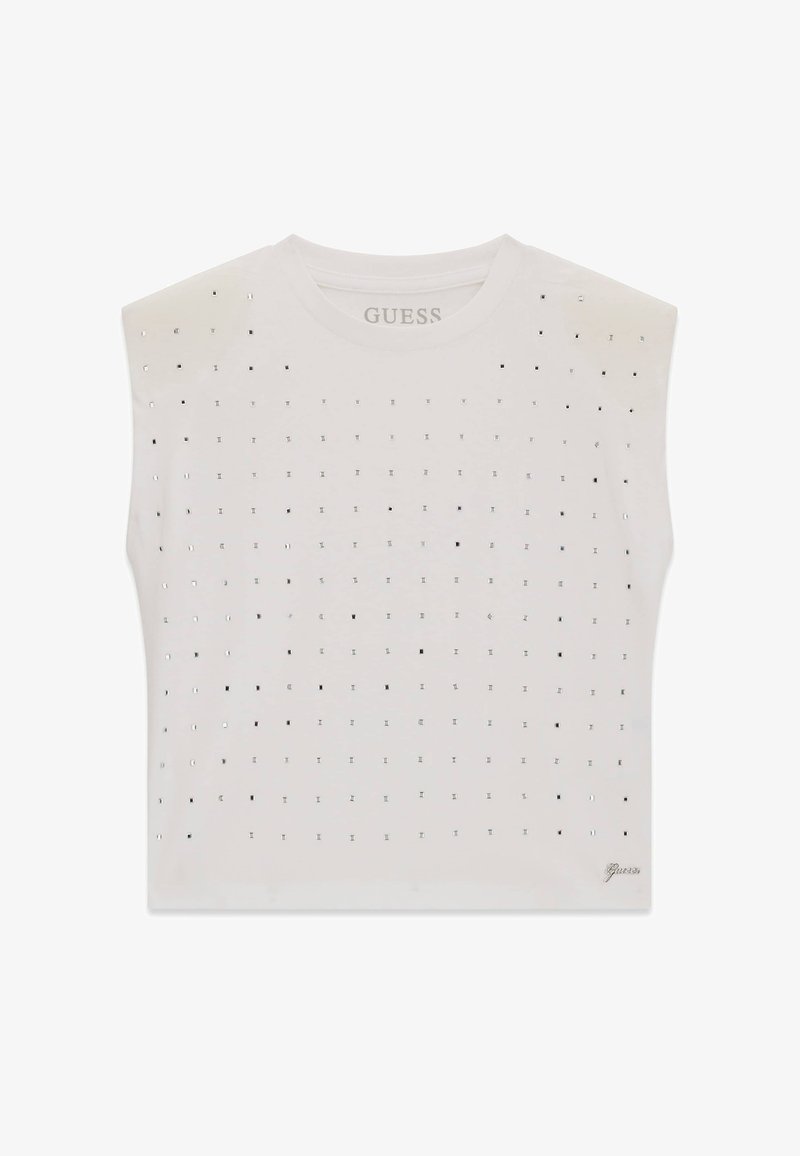 Haut blanc sans manches avec petits clous métalliques carrés disposés en motif quadrillé, encolure ronde et logo "Guess" en bas à droite.
