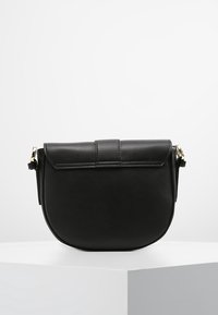 Sort læder crossbody taske med en rund form, flad klap, og en guld hardware accent. Glat tekstur med minimal syning.