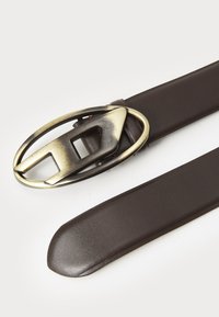 Brown leather belt featuring a metallic oval buckle with a geometric cutout design. Smooth texture and sleek shape.