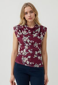 Top floreale bordeaux con scollatura drappeggiata, maniche a cappuccio e texture arricciata. Presenta fiori bianchi e gialli su uno sfondo ricco.