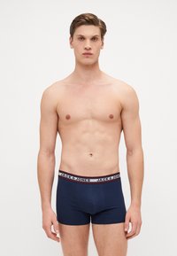 Marineblaue Boxershorts mit einem kontrastierenden elastischen Bund in Schwarz und Weiß mit der Aufschrift "JACK & JONES"; glattes Baumwollmaterial, enganliegendes Design.