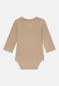 Beige μακρυμάνικη φόρμα μωρού με στρογγυλή λαιμόκοψη και κουμπώματα στο κάτω μέρος, απλωμένη επίπεδη σε λευκό φόντο.