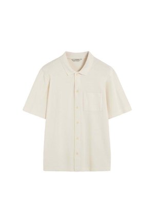 Camisa de manga corta y cuello en color crema pálido con una tela texturizada, que presenta un bolsillo frontal y cierre de botones.