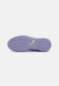 Suela de zapatilla deportiva morada con diseño texturizado, que presenta un prominente swoosh verde de Nike y patrones circulares de agarre.