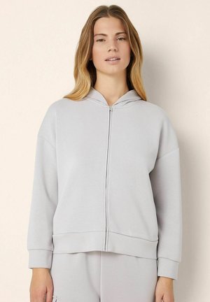 Lichtgrijze hoodie met rits aan de voorkant, regular fit, brede mouwen en een zachte, gladde textuur. Minimalistisch ontwerp, geen zichtbare patronen.