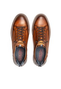 Zapatillas de cuero marrón con punta redondeada, diseño con cordones, costuras en contraste y un interior texturizado. Logo de la marca visible en la lengüeta.