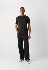 Sort bomulds t-shirt med korte ærmer, parret med løse sorte jeans og sorte sneakers med hvide såler. Afslappet pasform, minimalistisk design.