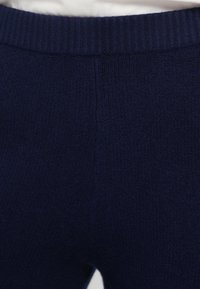 Navy blue knit pants with a ribbed waistband, featuring a soft texture and a close-fitting design. No pockets or visible hardware.