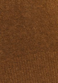 Tela de fieltro marrón con una superficie suave y texturada, que presenta longitudes de fibra variadas y un color uniforme y rico en toda su extensión.