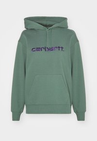 Zelená bavlněná mikina s kapucí a přední kapsou, s vyšitým fialovým logem "carhartt" přes hruď. Měkká textura a volný střih.