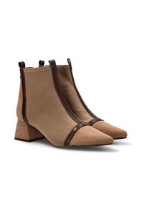Botas de tobillo marrones hechas de un tejido suave con acentos de ante. Punta afilada, tacones de bloque y correas decorativas marrones en los lados.