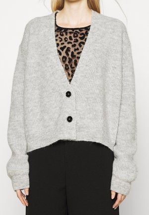 Lichtgrijze gebreide cardigan met een cropped ontwerp, diepe V-hals en twee zwarte knopen. Heeft lange, oversized mouwen en een geribbelde textuur.