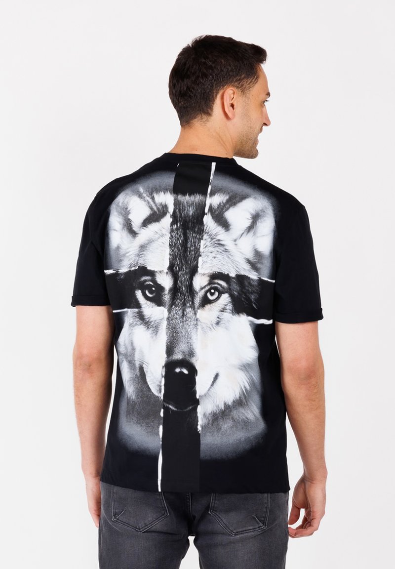 Camiseta negra con un gran gráfico detallado de un lobo en la parte posterior. Mangas cortas, cuello redondo, hecha de algodón y con una textura suave.